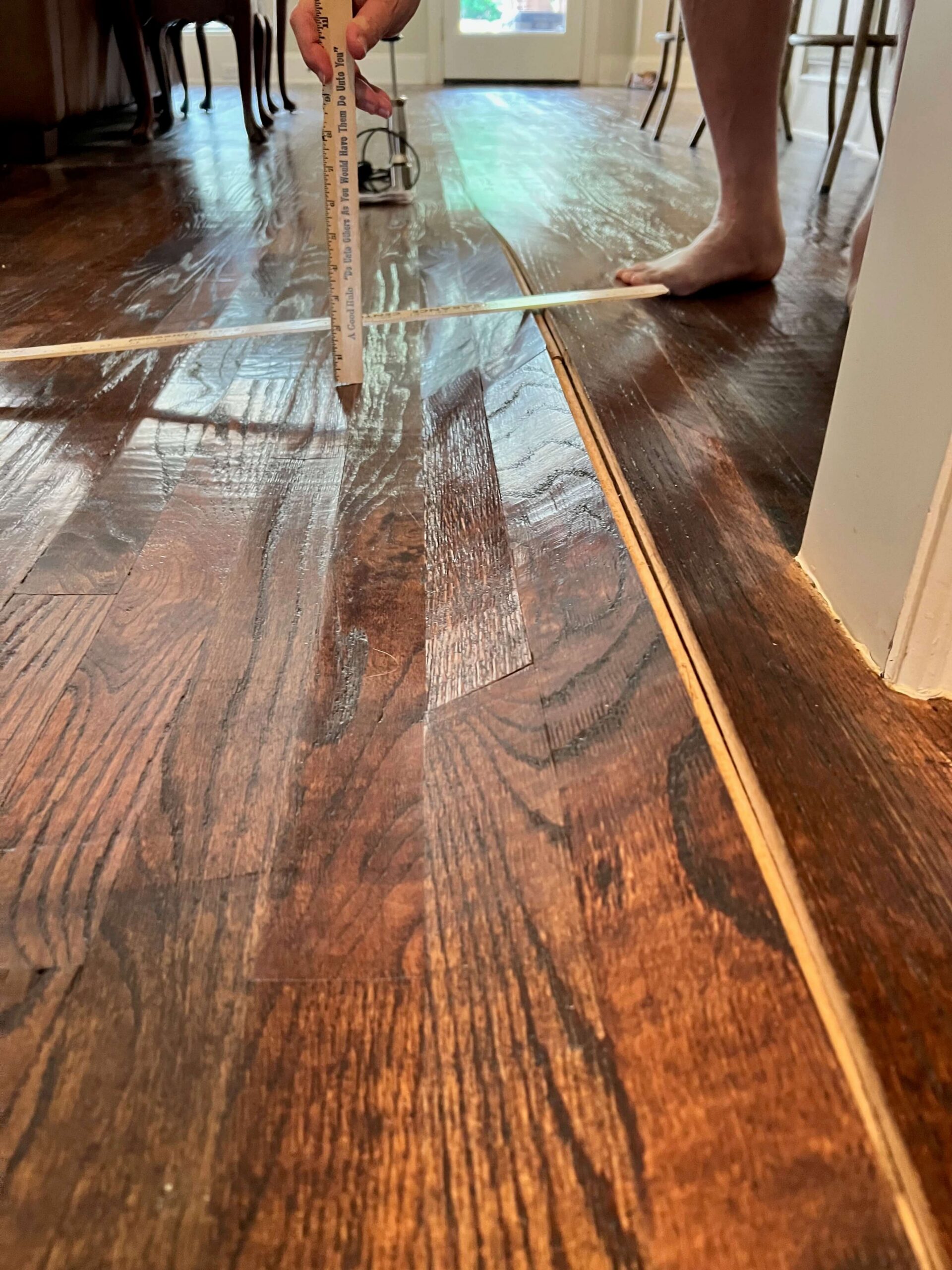 Buckling and warping hardwood floor being measured after water damage