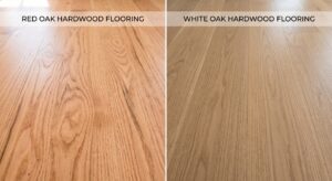 A split-screen photograph comparing Red Oak and White Oak hardwood flooring side-by-side in natural light. The left panel, labeled "RED OAK HARDWOOD FLOORING," displays planks with warm, reddish-orange tones and prominent, swirly grain patterns. The right panel, labeled "WHITE OAK HARDWOOD FLOORING," shows planks with cooler, tan-brown tones and a tighter, linear grain structure. A central vertical line divides the comparison.